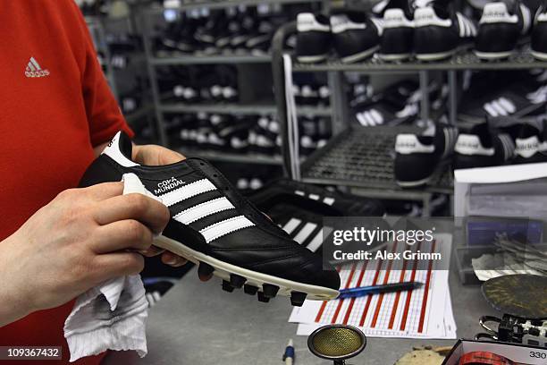 An employee examines football boots at the final check of the factory of German sporting-goods maker Adidas AG on February 23, 2011 in Scheinfeld,...