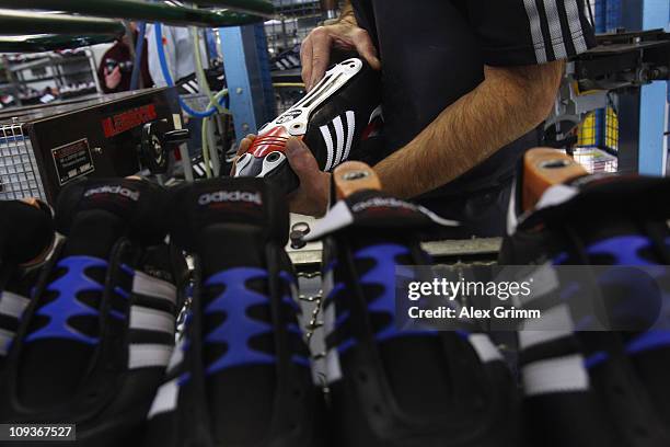 Employee Ingo Meixner attaches the shoe sole on a handmade football boot at the factory of German sporting-goods maker Adidas AG on February 23, 2011...