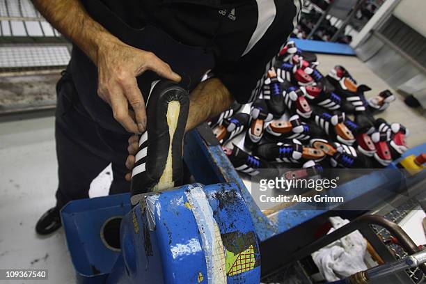 Employee Ingo Meixner removes excrescent glue from a handmade football boot at the factory of German sporting-goods maker Adidas AG on February 23,...