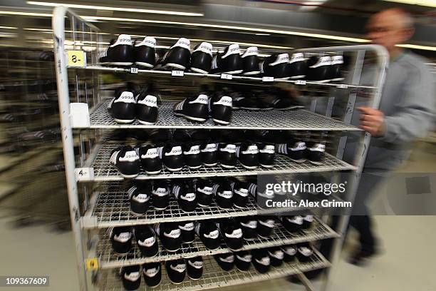 An employee pushes a cart with handmade football boots at the factory of German sporting-goods maker Adidas AG on February 23, 2011 in Scheinfeld,...