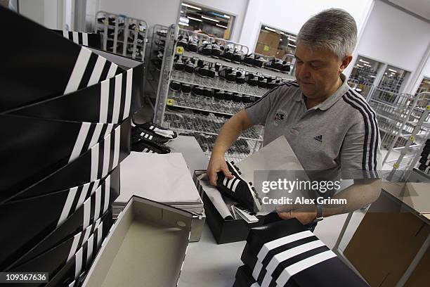 An employee packages handmade football boots at the factory of German sporting-goods maker Adidas AG on February 23, 2011 in Scheinfeld, Germany. The...