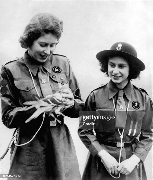 Picture taken on 1943 showing Princess Elizabeth, the futur Queen Elizabeth II, with her sister Princess Margaret admiring a pigeon before its...