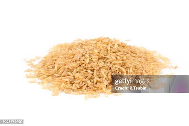 pile of brown rice isolated on white - arroz integral fotografías e imágenes de stock