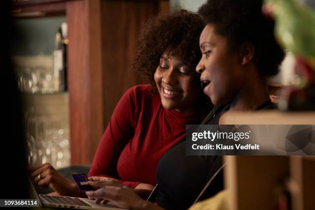 young women ordering christmas gifts online with creditcard - middle sibling stock pictures, royalty-free photos & images