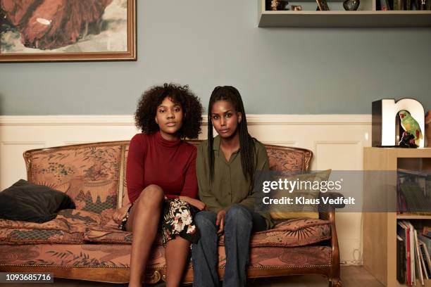 two young women in sofa at home - tough love stock-fotos und bilder
