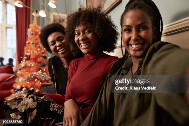 three young women making selfie in sofa at home - xmas together stock-fotos und bilder