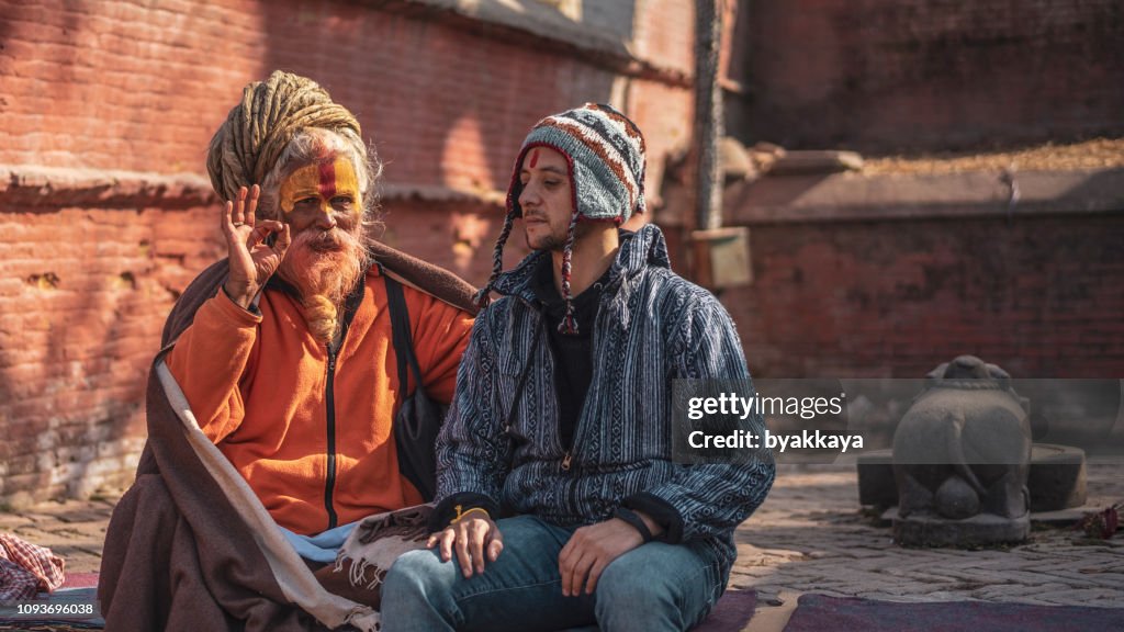 パシュパティナート寺院で聖職者と座っての帽子の男