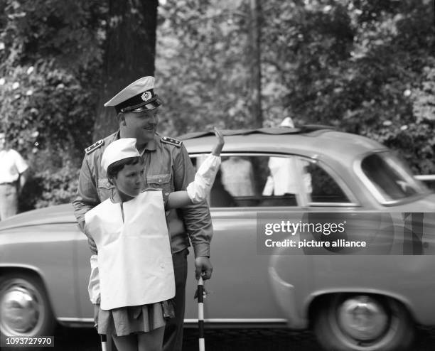 Auf einer Straßenkreuzung in Leipzig darf eine Schülerin im Juli 1977 mit einem Volkspolizisten den Verkehr regeln. Kleine Schülerlotsen waren auf an...