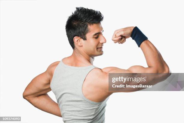 studio shot of young man flexing muscles - muscular arm stock pictures, royalty-free photos & images
