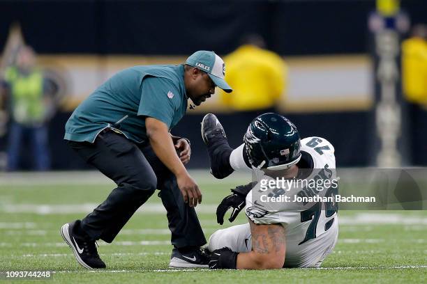 Brandon Brooks of the Philadelphia Eagles is tended to by the trainer after sustaining a second quarter injury against the New Orleans Saints in the...