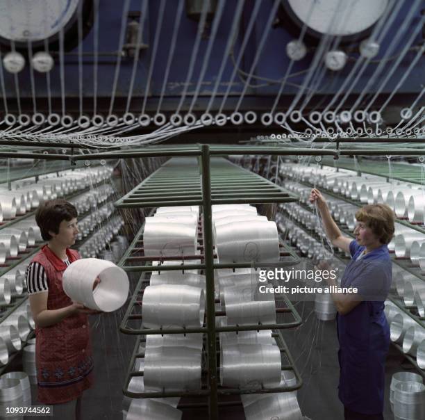 Zwei Arbeiterinnen kontrollieren in der Mattenabteilung des VEB Glasseidenwerks Oschatz die Glasfaserfäden, die von den Spulen zur Mattenverarbeitung...