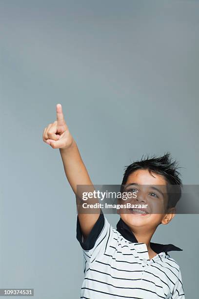 boy (6-7) smiling and pointing up - indian boy portrait stockfoto's en -beelden