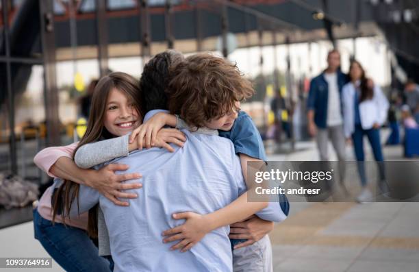 happy kids greeting their father at the airport after a trip - family at airport stock pictures, royalty-free photos & images