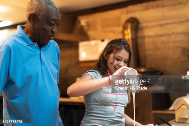 nonno ispano-latino che insegna al nipote come cucinare a casa - stanno preparando il brigadeiro brasiliano - condensed milk foto e immagini stock