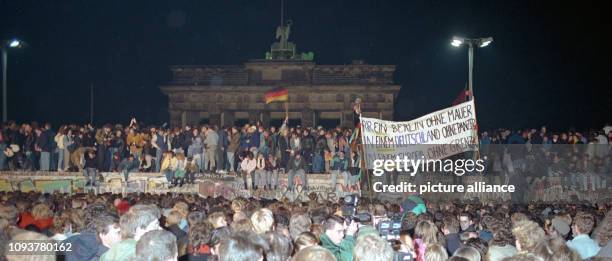 Einen Tag nach der Grenzöffnung in Berlin feiern tausende Menschen auf, vor und hinter der Berliner Mauer am Brandenburger Tor, aufgenommen am 10....