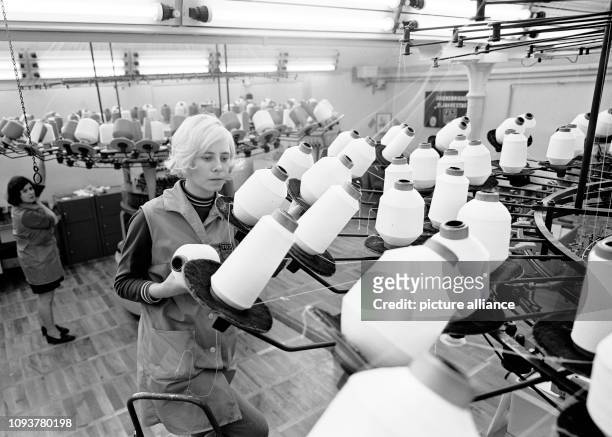 Zwei Arbeiterinnen an Textilmaschinen in eine Werkhalle im VEB Palla Textilwerke Meerane im früheren DDR-Bezirk Karl-Marx-Stadt, aufgenommen 1982. In...