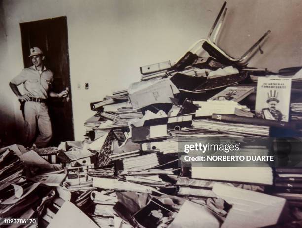 Reproduction of a picture taken in 1992 in which a policeman guards a pile of documents that forms part of the "Archives of Terror", is seen at the...