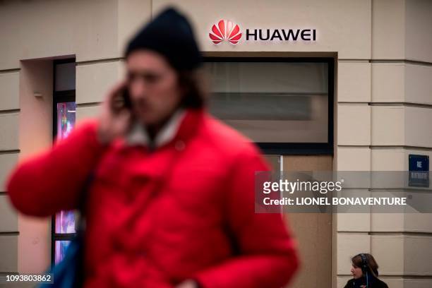 People pass by a Huawei logo above the entrance of a Huawei store in Paris on February 4, 2019. - A government amendment to establish a...