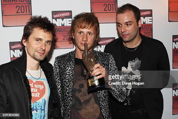 Christopher Wolstenholme, Dominic Howard and Matt Bellamy of Muse pose in front of the winners boards at the Shockwaves NME Awards 2011 held at...