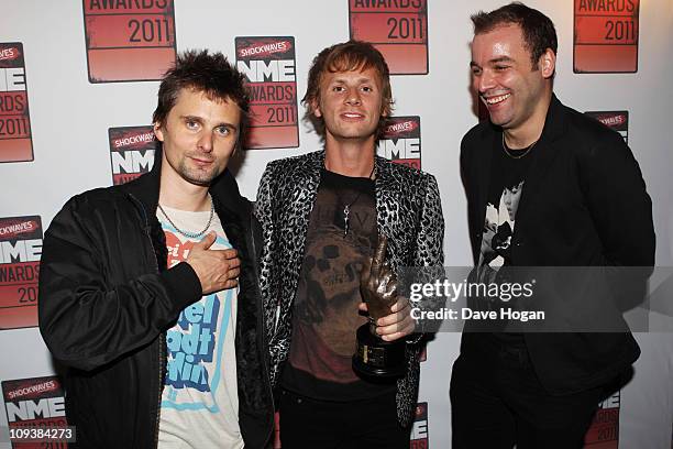 Christopher Wolstenholme, Dominic Howard and Matt Bellamy of Muse pose in front of the winners boards at the Shockwaves NME Awards 2011 held at...