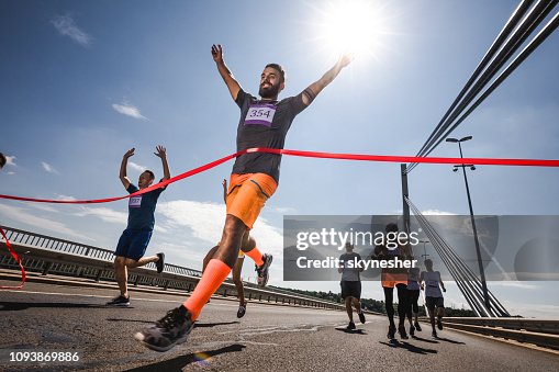 Low angle view of successful man crossing the finish line on marathon race. Low angle view of successful man crossing the finish line on marathon race.
