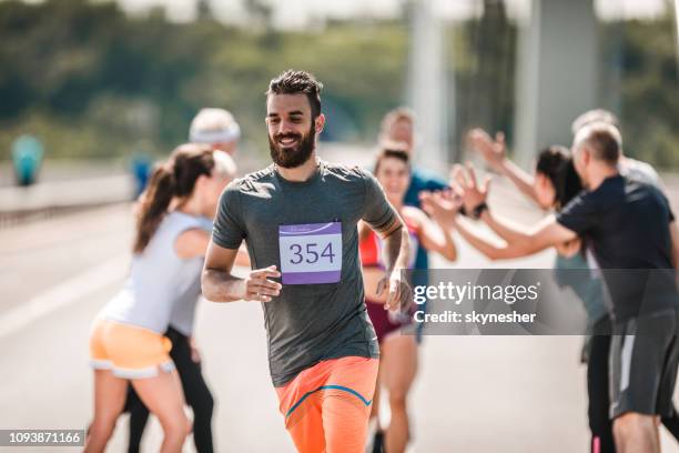 happy man running a marathon race on the road. - road running stock pictures, royalty-free photos & images