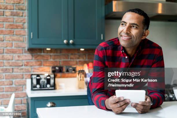 thoughtful man with digital tablet in kitchen - fashion man single casual shirt imagens e fotografias de stock