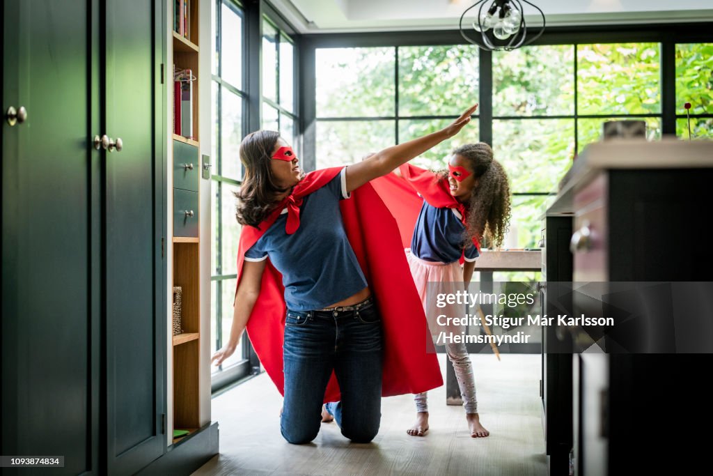 Girl with mother in red superhero costume at home