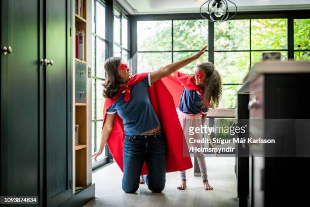 girl with mother in red superhero costume at home - superman stock pictures, royalty-free photos & images