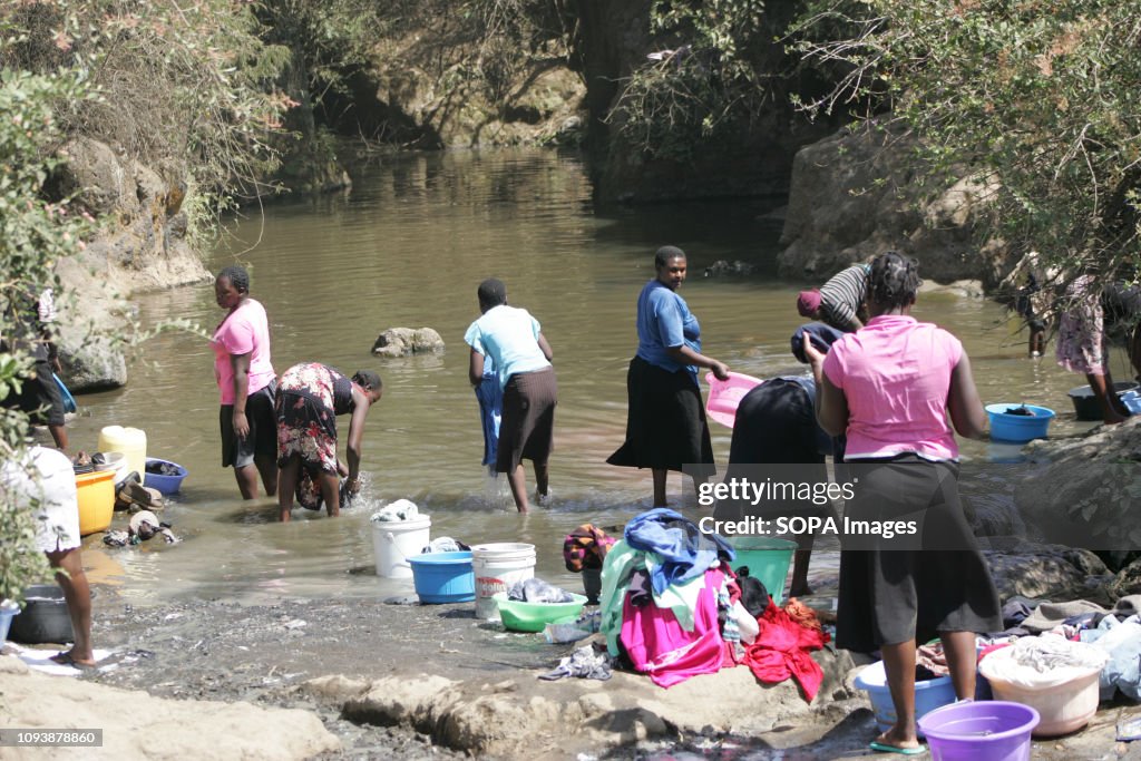 Women are seen washing clothes in a river where they draw...