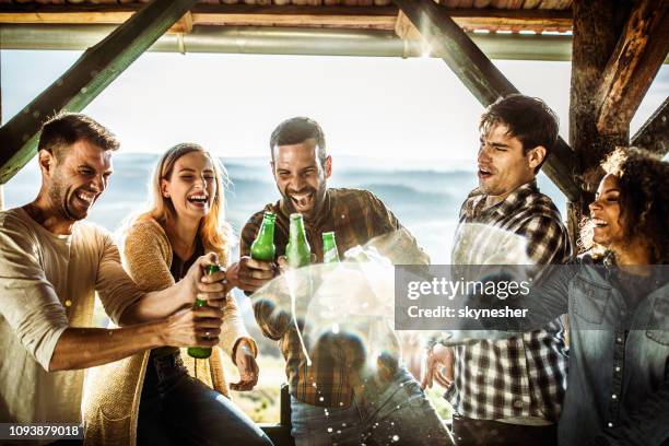 playful friends having fun with beer on a balcony. - beer splash stock pictures, royalty-free photos & images