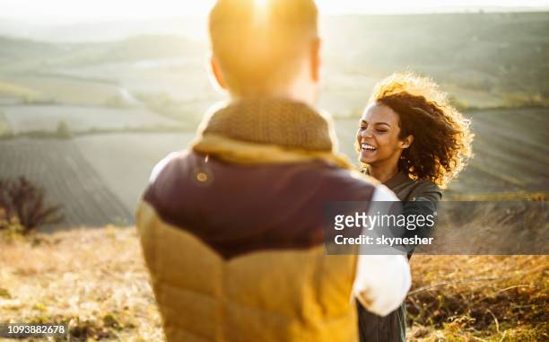 cheerful woman having fun while spinning with her boyfriend in a meadow. - fall fun stock pictures, royalty-free photos & images