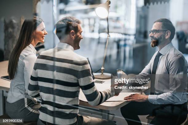 happy couple shaking hands with real estate agent in the office. - banking stock pictures, royalty-free photos & images