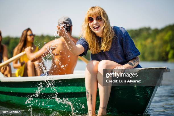 woman enjoying boat ride in lake - man splashed with colour stock pictures, royalty-free photos & images