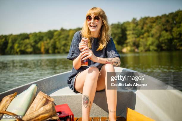 smiling woman holding beer on rowboat - blonde youth culture stock pictures, royalty-free photos & images