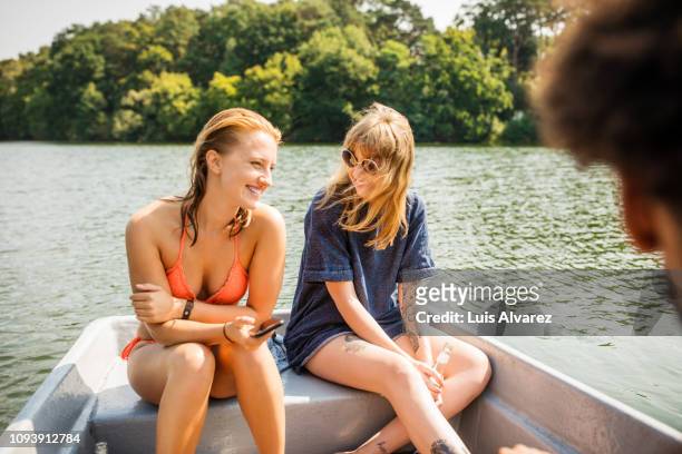 female friends sitting in a row boat and chatting - women in see through dresses stock-fotos und bilder
