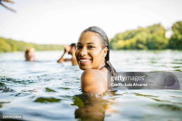 smiling woman in a lake with friends - swimming stock-fotos und bilder