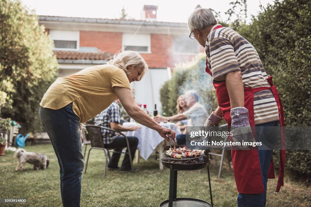 Senior People Friends Enjoying Backyard Barbecue High-Res Stock