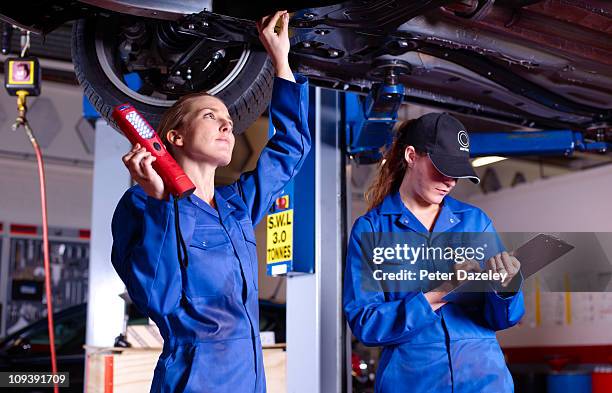 female mechanics underneath car doing service - mot garage stock pictures, royalty-free photos & images