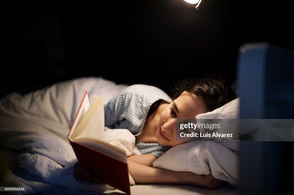 Woman reading book in bed