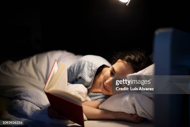 woman reading book in bed - good night imagens e fotografias de stock