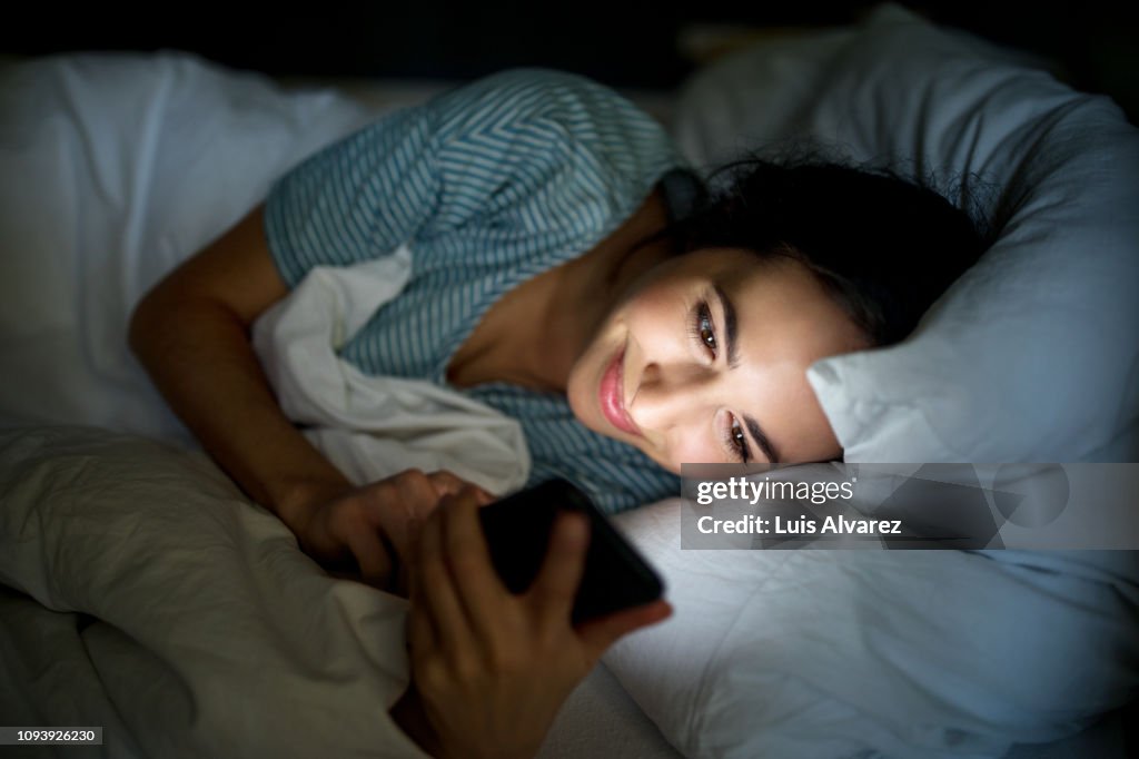 Woman in bed checking her mobile phone