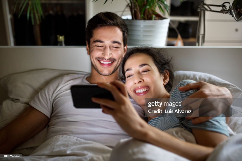 Couple watching movie on smartphone in bed