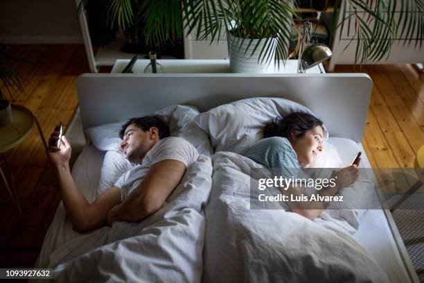 couple in bed using their mobile phones - couple in bed ストックフォトと画像