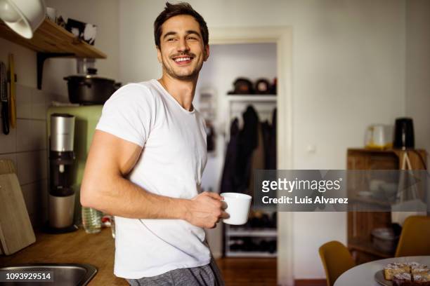 young man in kitchen with coffee - lässige kleidung stock-fotos und bilder