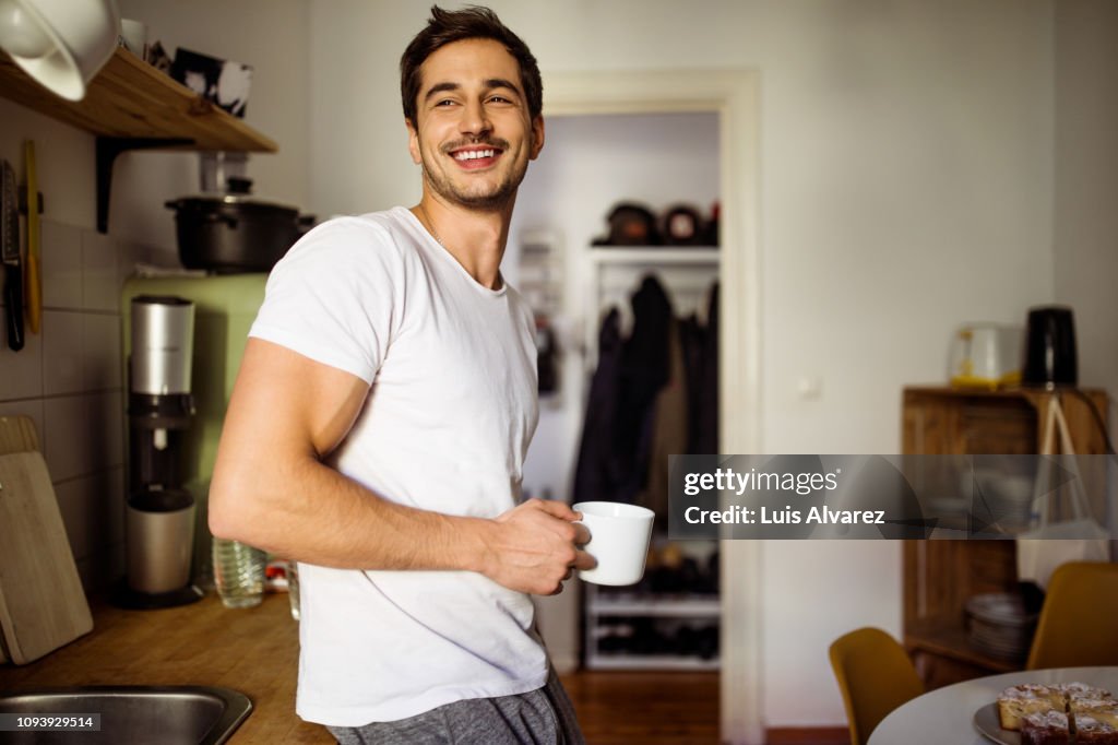 Young man in kitchen with coffee