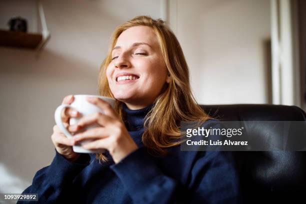 smiling woman having coffee at home - coffee at home stock-fotos und bilder
