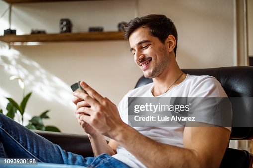 Young man using smart phone at home Young man using smart phone at home