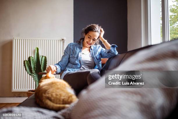 woman relaxing on sofa with her cat - cat indoors stock pictures, royalty-free photos & images