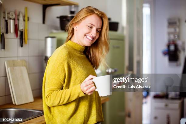 woman in kitchen with coffee - woman drinking phone kitchen stockfoto's en -beelden